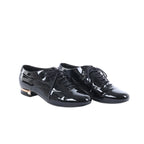 Black Chanel patent leather lace-up shoes displayed beside a black Chanel box, dust bags and white cards.