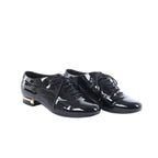 Black Chanel patent leather lace-up shoes displayed beside a black Chanel box, dust bags and white cards.