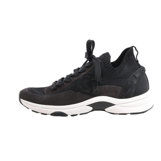 Side view of black CHANEL Coco Mark Knit Sneakers in size 40.5 EU, featuring a mixed-material upper with mesh, suede, and knit textures, tonal laces, and a white chunky sole, with the iconic CC logo on the side.