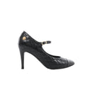 Side view of a black Chanel quilted leather pump with a smooth cap toe, slim high heel, buckled strap and gold-tone floral embellishment.