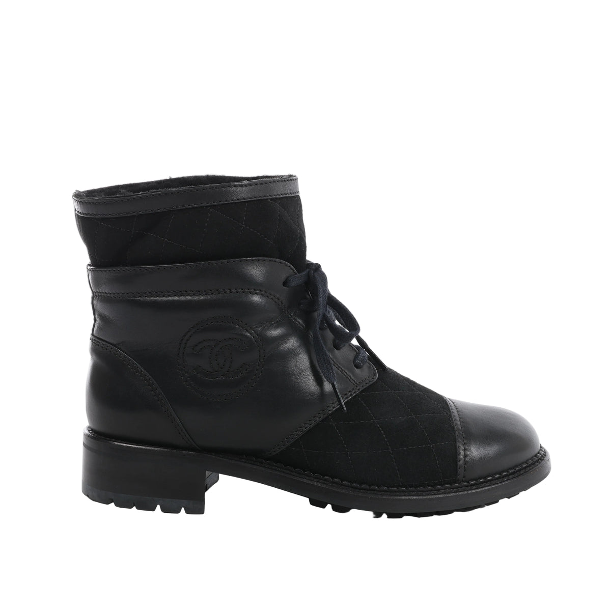 Side view of a black Chanel ankle boot with quilted suede panels, leather toe cap, stitched CC logo, black laces and a low block heel.