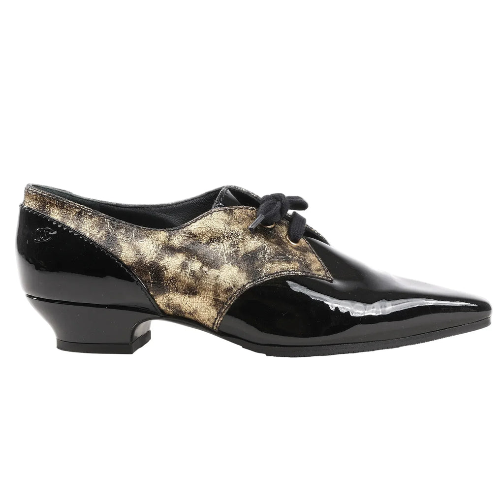 Chanel Coco Mark loafers in black patent leather with distressed gold panels, lace-up front, low heel, and subtle CC logo on the heel. Side view, size 37 EU, model G34275.