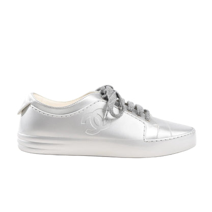 Chanel Coco Mark sneakers in metallic silver rubber featuring tonal laces, embossed CC logo on the side, and a smooth round-toe silhouette. Side view, size 38 EU, model G32719.