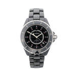 Chanel J12 automatic watch with glossy black ceramic bracelet, black dial, rotating bezel with silver-tone numerals, and pink gemstone hour markers.