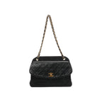 Front view of Chanel black quilted leather shoulder bag with a curved flap, gold-tone CC turn-lock and leather-threaded gold-tone chain strap.