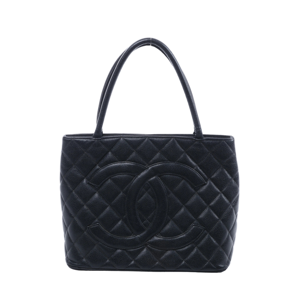 Black Chanel caviar leather shoulder bag with diamond quilting, oversized interlocking CC logo and two long handles on a white background.