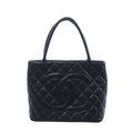 Black Chanel caviar leather shoulder bag with diamond quilting, oversized interlocking CC logo and two long handles on a white background.