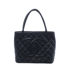 Black Chanel caviar leather shoulder bag with diamond quilting, oversized interlocking CC logo and two long handles on a white background.