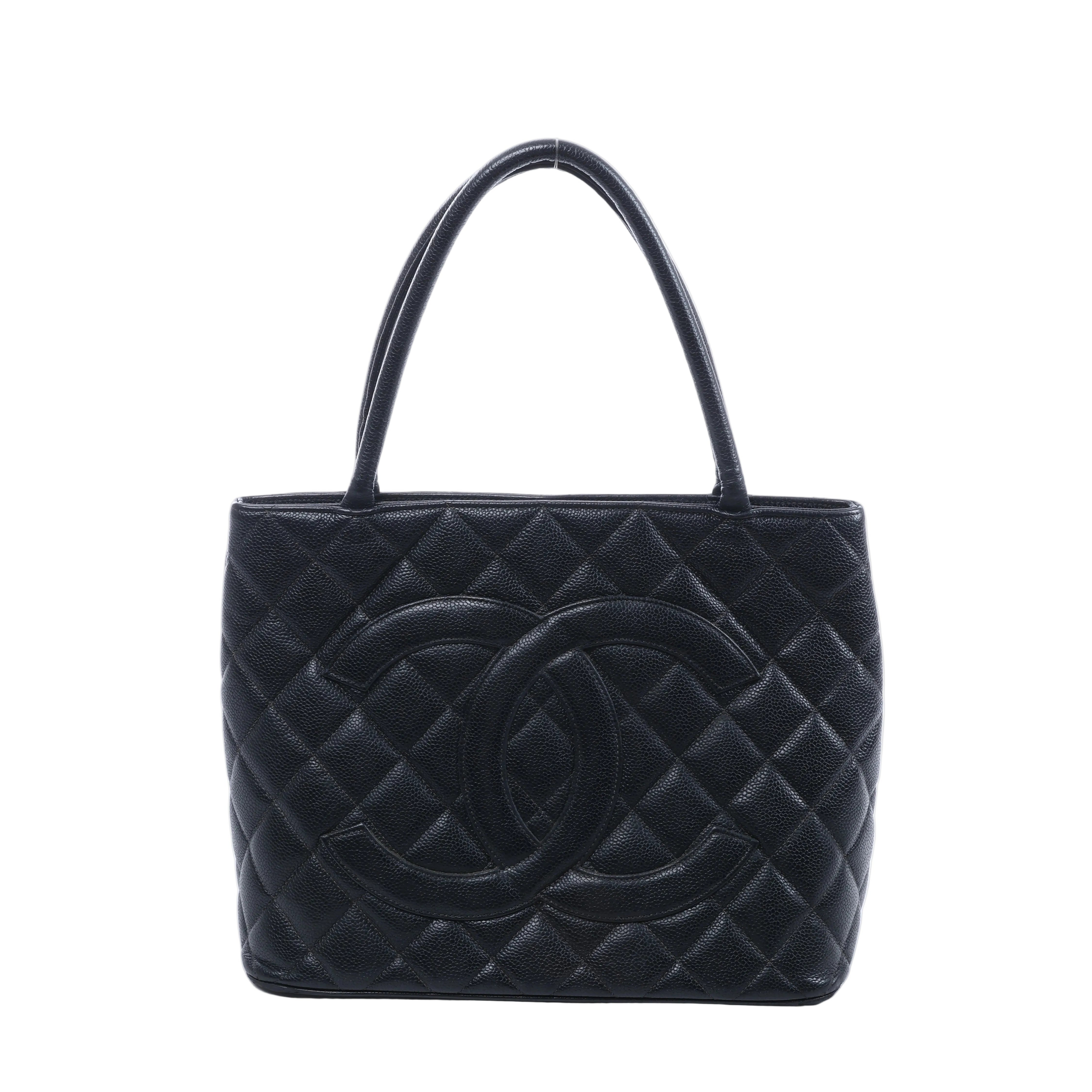 Black Chanel caviar leather shoulder bag with diamond quilting, oversized interlocking CC logo and two long handles on a white background.