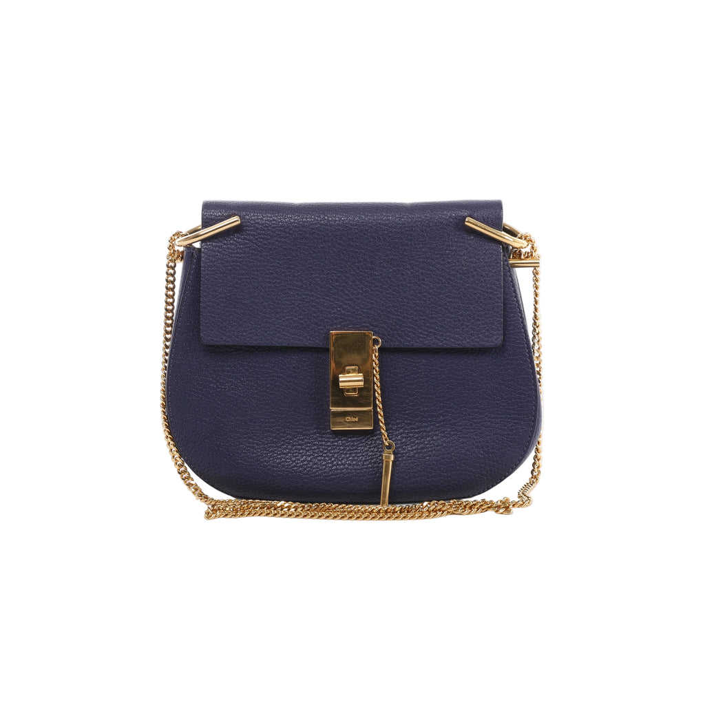 Purple Chloé Drew grained leather bag with a front flap, gold-tone clasp and hanging pin detail, with its chain strap arranged around the sides and base.