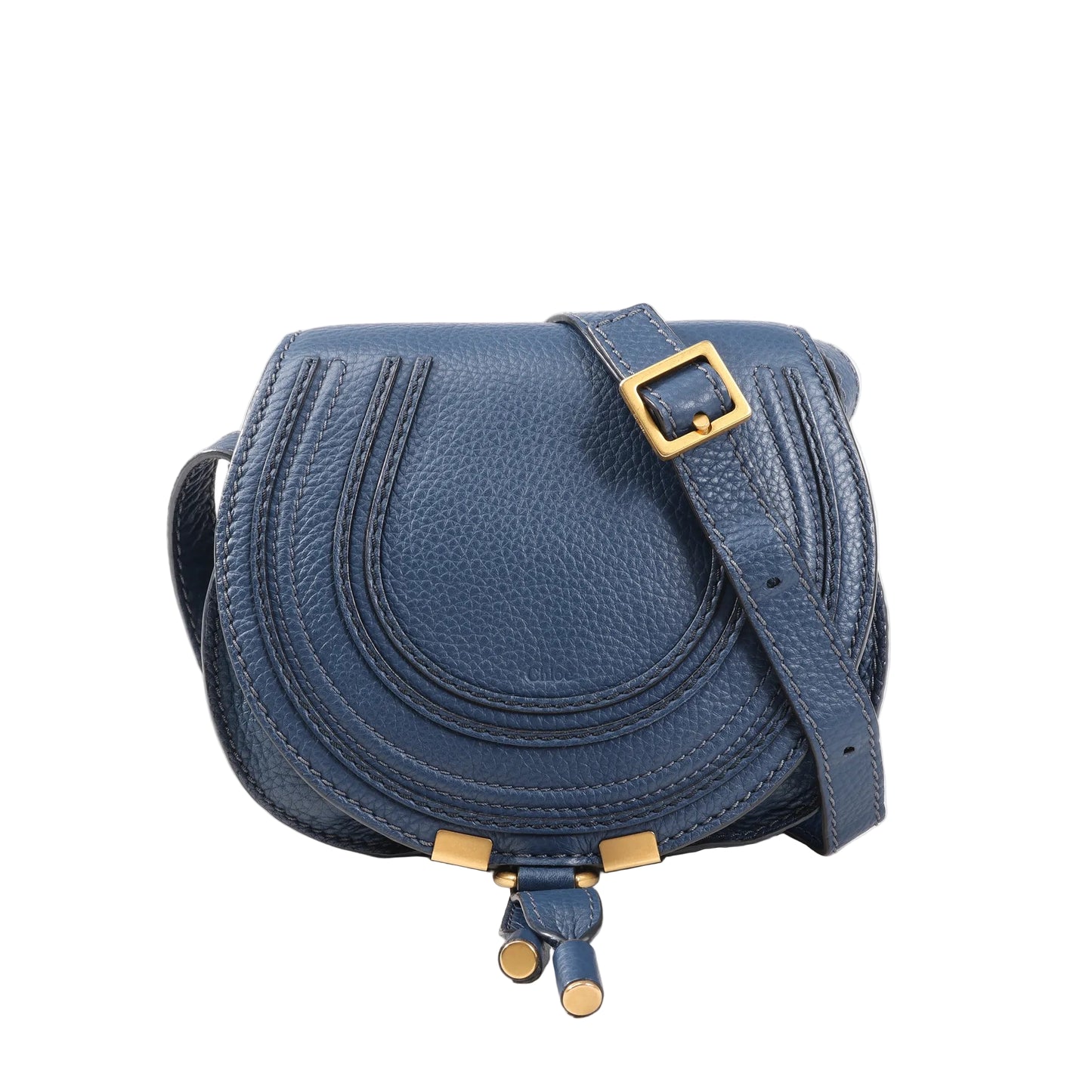 Front view of a Chloé Marcie Mini crossbody bag in navy blue grained leather, featuring curved stitching detail, a flap closure, gold-tone hardware, and an adjustable leather strap.