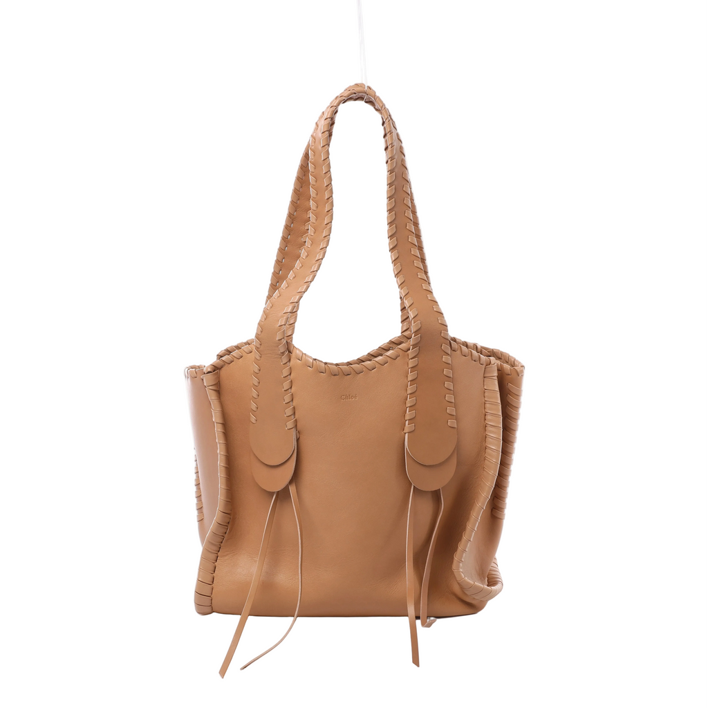 Brown Chloé Mony leather tote with long shoulder handles, whipstitched edges, hanging leather ties and a small embossed Chloé logo on the front.