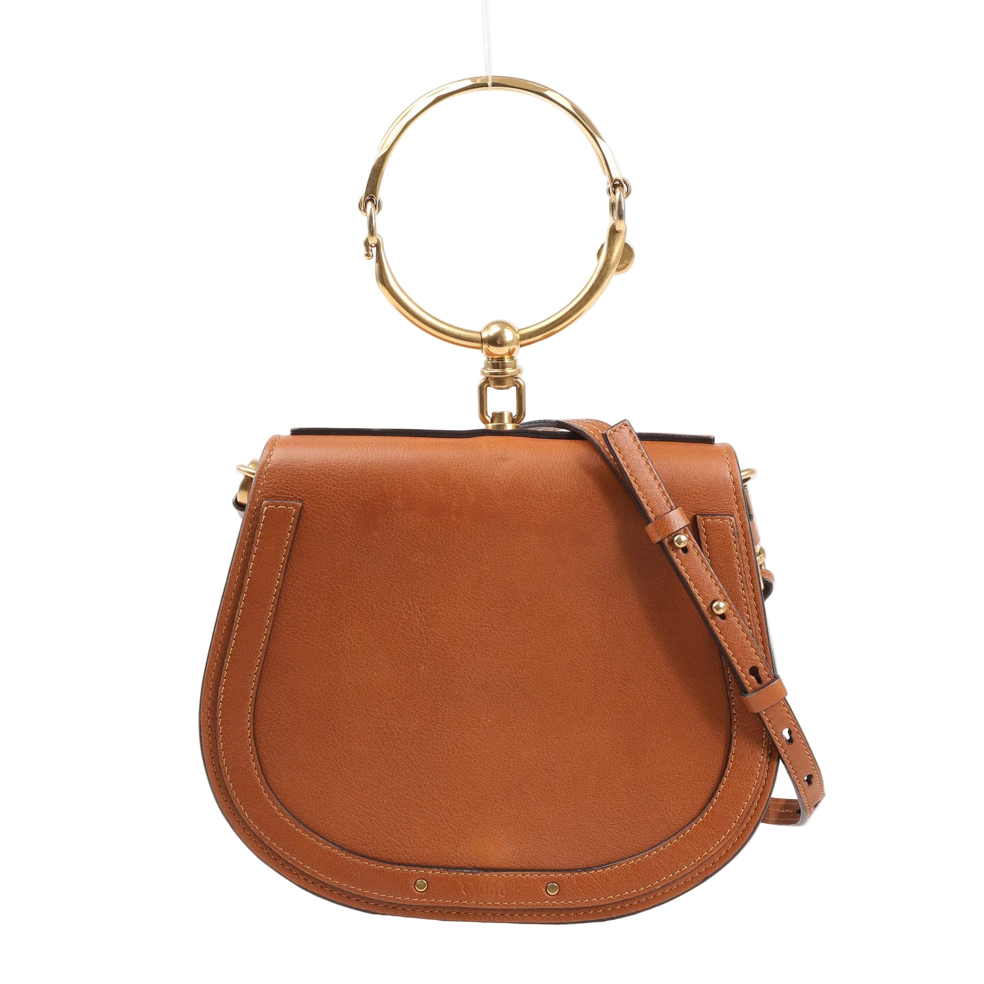 Front view of a Chloé Nile Small 2Way bag in brown leather featuring a rounded saddle shape, gold-tone metal bracelet handle, adjustable leather shoulder strap, and stitched trim details.