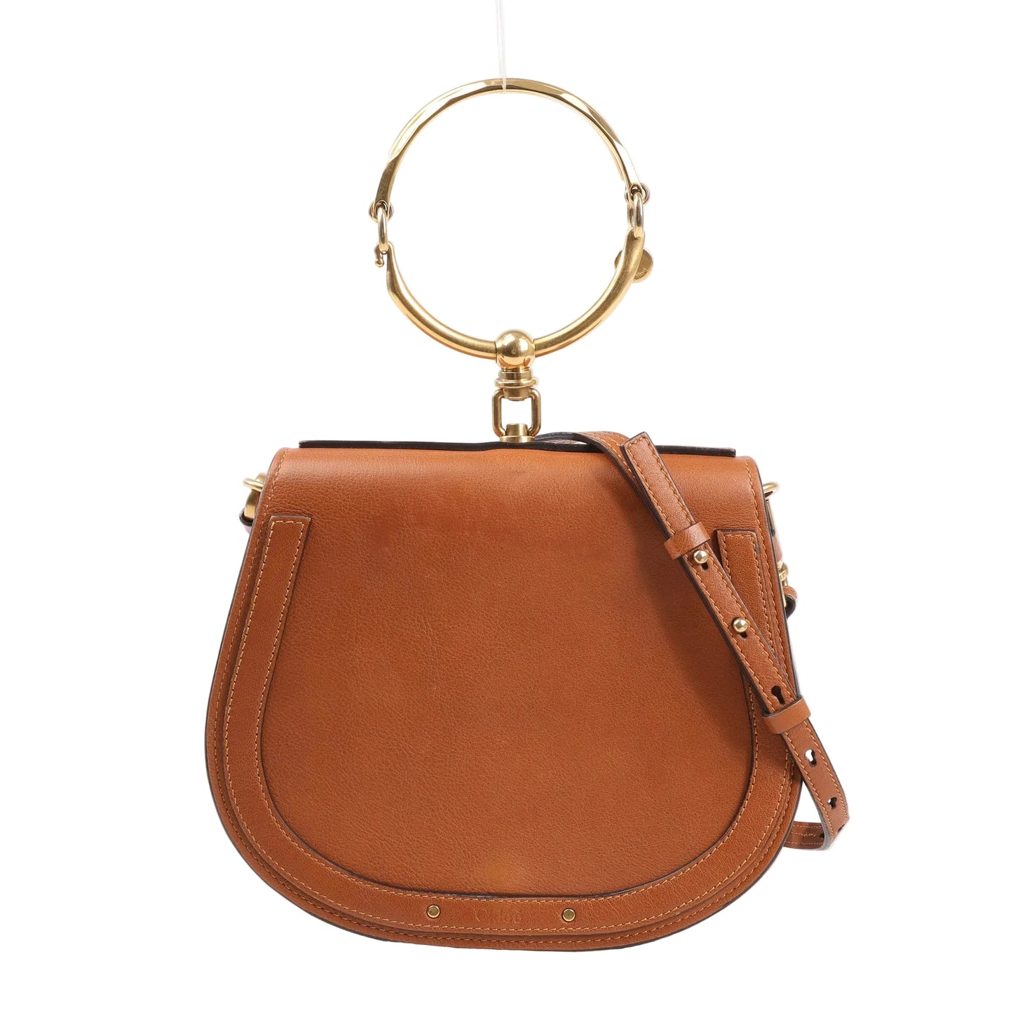 Front view of a Chloé Nile Small 2Way bag in brown leather featuring a rounded saddle shape, gold-tone metal bracelet handle, adjustable leather shoulder strap, and stitched trim details.