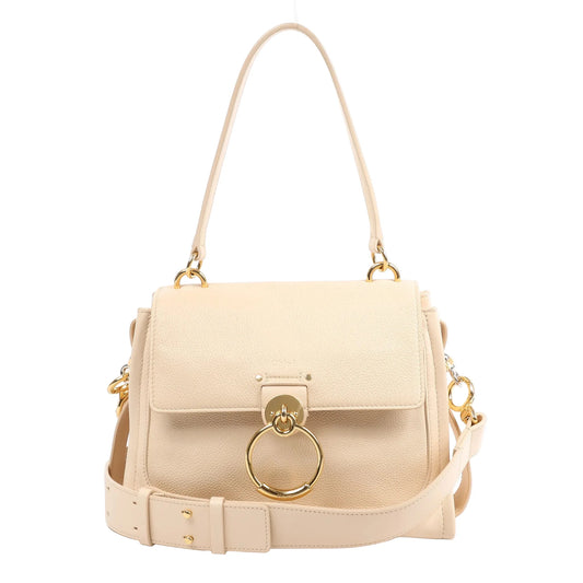 Front view of a Chloe Tess Day 2Way Handbag in beige grained leather, featuring a structured silhouette, front flap with gold-tone ring closure, top handle, and detachable shoulder strap, displayed against a white background.