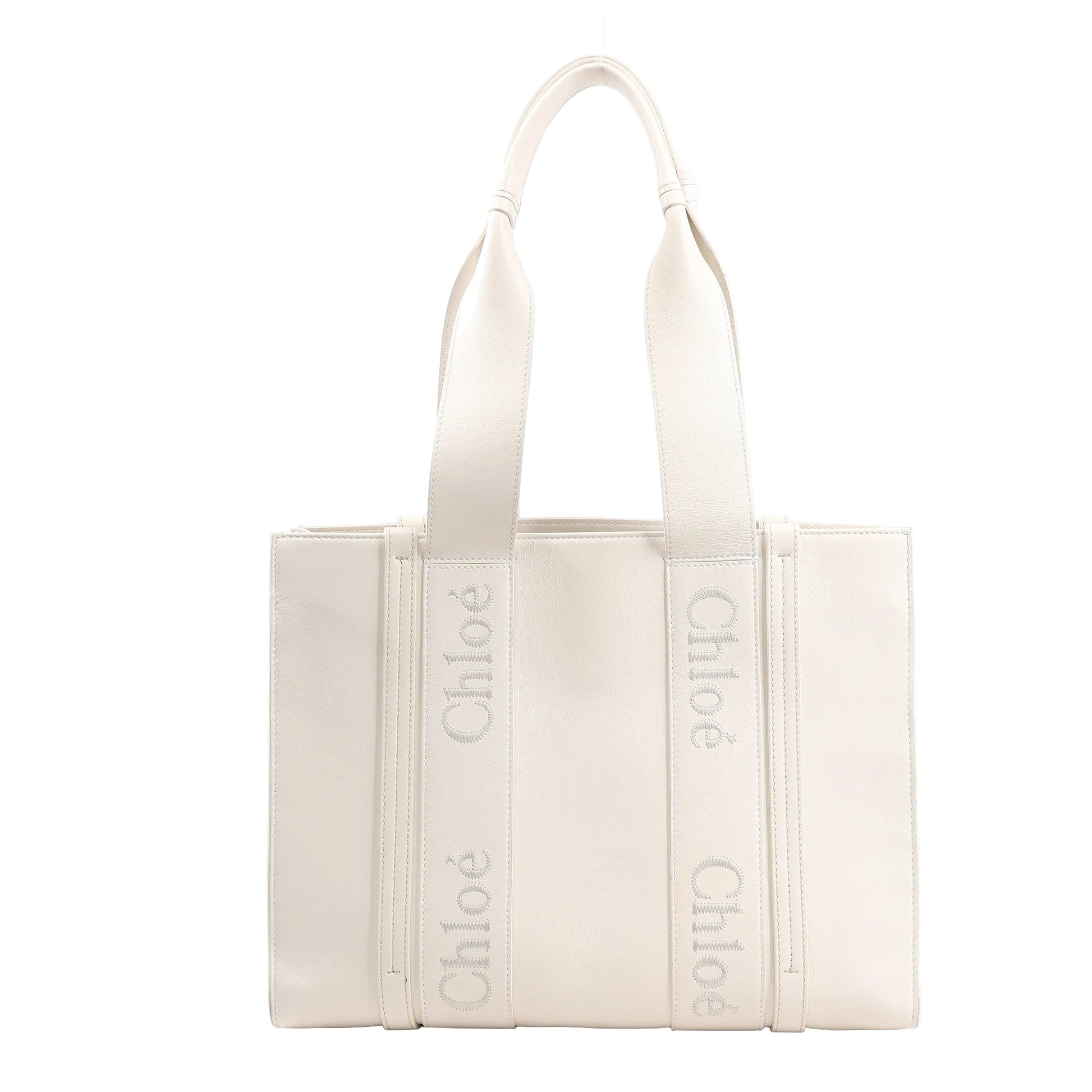 Chloé Woody Medium handbag in white leather featuring structured sides, two top handles with Chloé logo webbing, and a clean, minimalist silhouette.