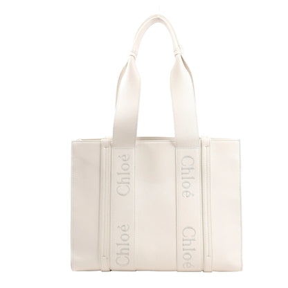 Chloé Woody Medium handbag in white leather featuring structured sides, two top handles with Chloé logo webbing, and a clean, minimalist silhouette.