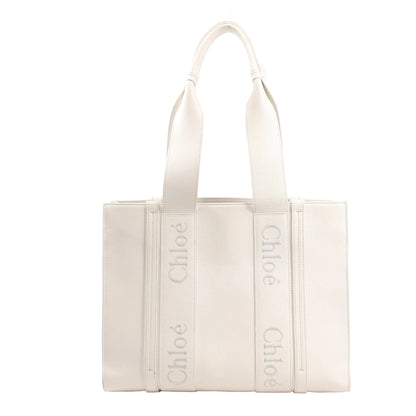Chloé Woody Medium handbag in white leather featuring structured sides, two top handles with Chloé logo webbing, and a clean, minimalist silhouette.