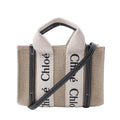 Chloé Woody Mini beige canvas handbag with black leather trim, cream logo webbing handles and a detachable black shoulder strap.