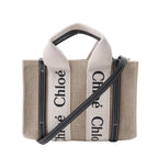 Chloé Woody Mini beige canvas handbag with black leather trim, cream logo webbing handles and a detachable black shoulder strap.