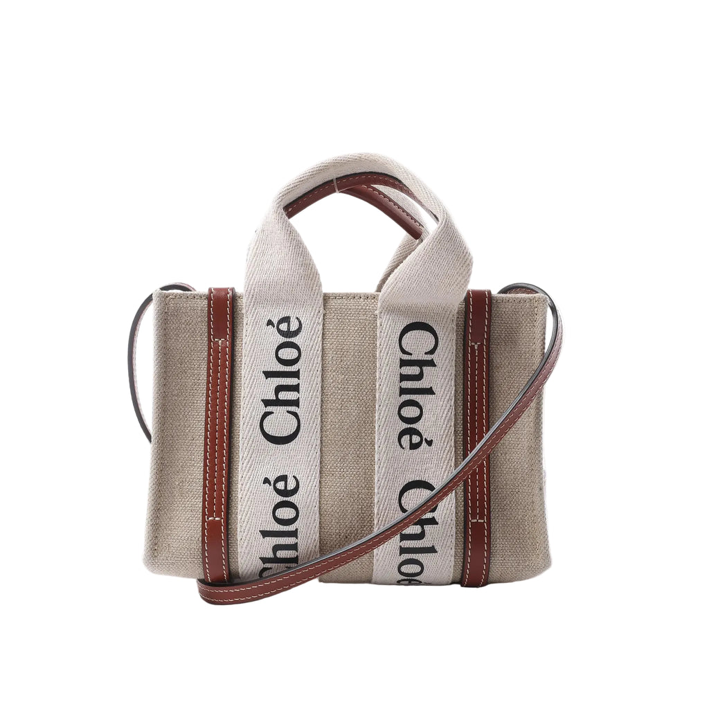 Chloé Woody Mini handbag in beige canvas with brown leather trim, logo webbing top handles and a slim detachable shoulder strap.