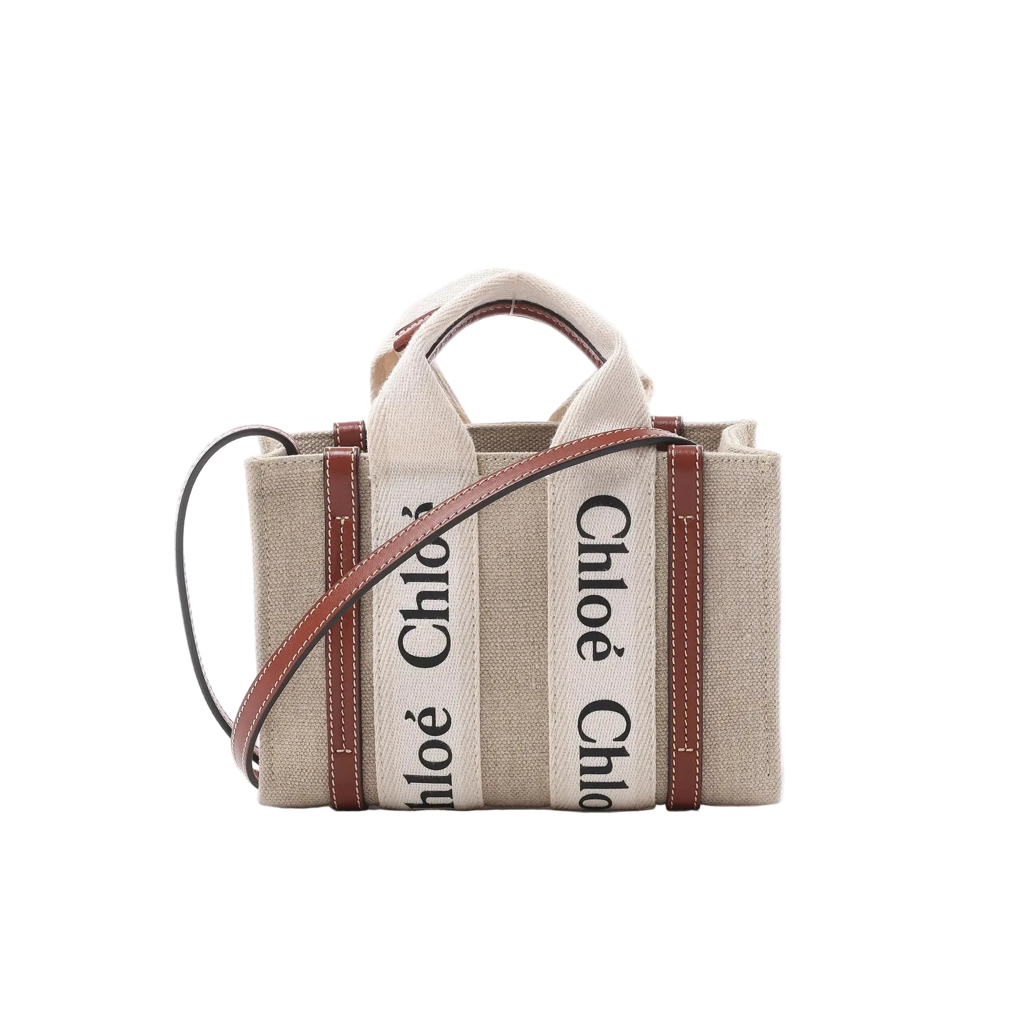 Front view of Chloé Woody Nano tote in beige canvas with vertical “Chloé” logo webbing, brown leather trim, top handles, and a brown leather shoulder strap.