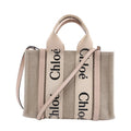Chloé Woody Small handbag in beige canvas with pale pink leather trim, black logo webbing handles and a detachable shoulder strap.