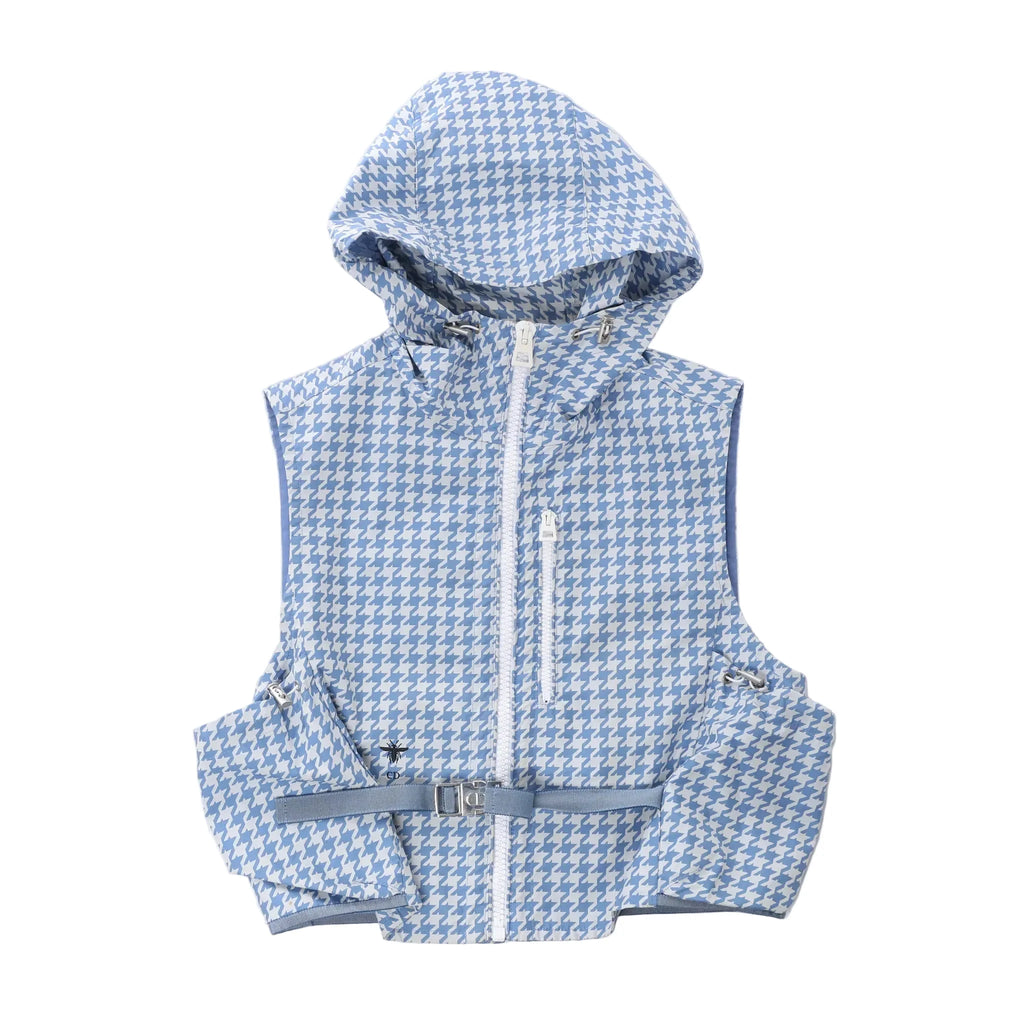 Christian Dior sleeveless hooded vest in blue and white houndstooth pattern with front zip closure, chest zip pocket, utility pockets and adjustable waist belt on white background.
