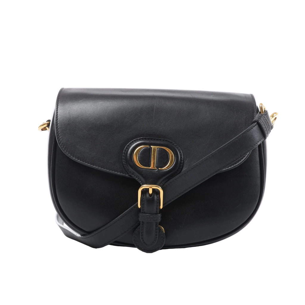 Front view of a black Christian Dior Bobby leather crossbody bag with a rounded flap, gold-tone CD initials, buckle detail and leather strap.
