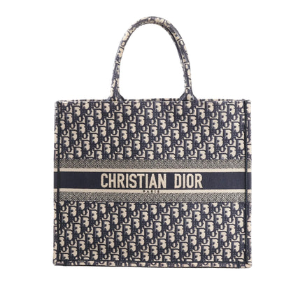 Front view of the Christian Dior Book Tote Large in navy blue Oblique canvas, featuring all-over "Dior" monogram print and bold "CHRISTIAN DIOR PARIS" branding across the center.