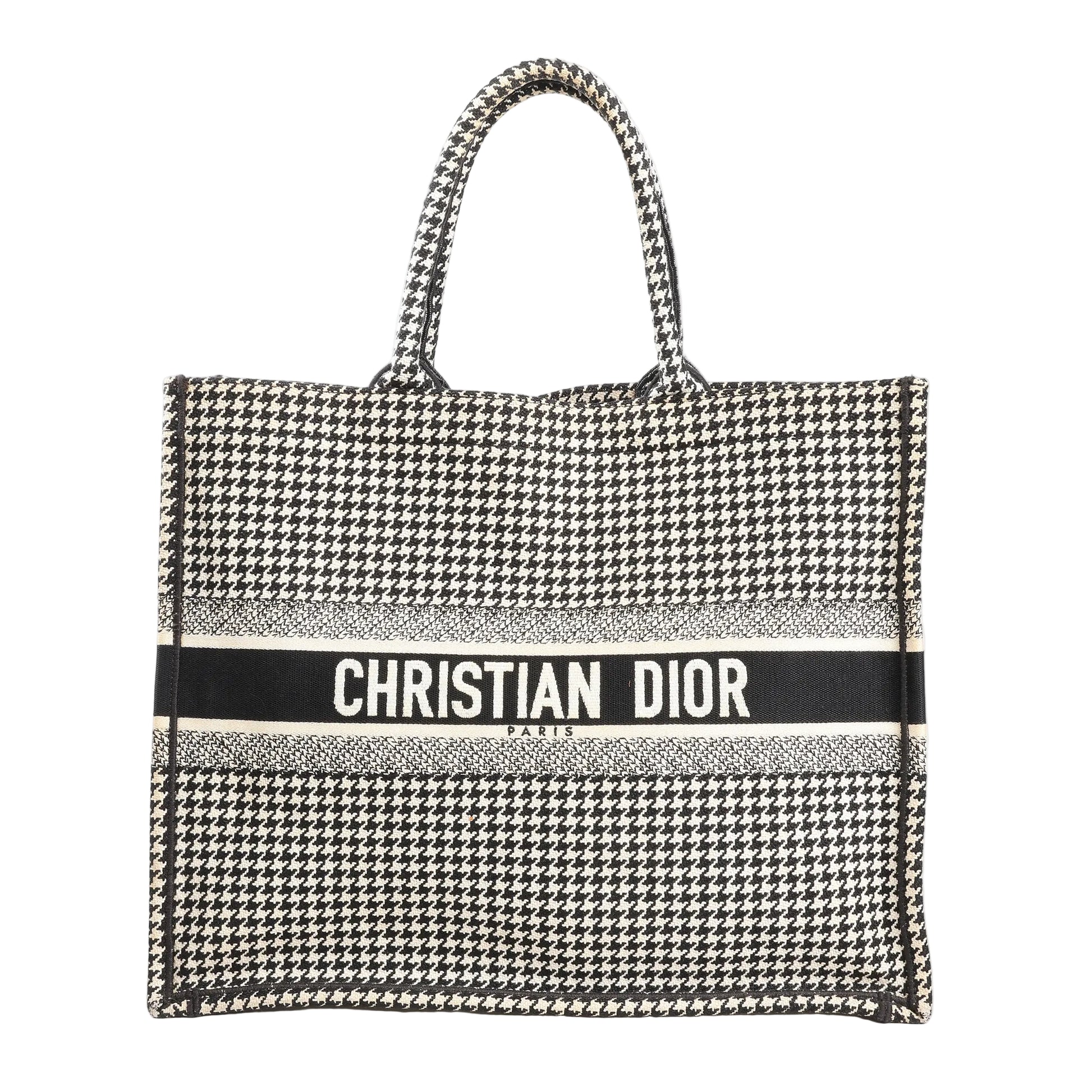 Christian Dior Book Tote Large canvas shoulder bag in black and white featuring an all-over houndstooth pattern with “CHRISTIAN DIOR PARIS” embroidered across the front and dual top handles.