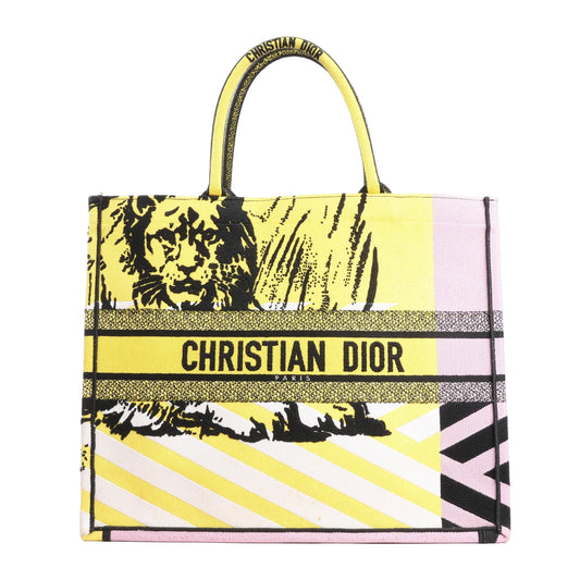 Christian Dior Book Tote Large shoulder bag in yellow and purple canvas featuring bold black lion motif, signature "CHRISTIAN DIOR PARIS" embroidery, and dual top handles.