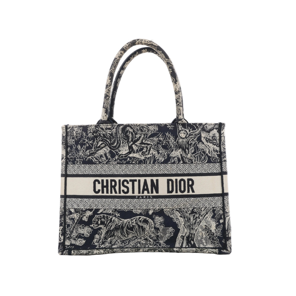 Front view of Christian Dior Book Tote Medium with navy and beige animal and foliage embroidery, matching twin handles and a Christian Dior Paris logo band.