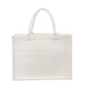 White Christian Dior Book Tote Medium canvas bag with tonal geometric embroidery, dual top handles and CHRISTIAN DIOR lettering across the front.