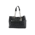 Front view of Dior Soft Lady Dior Large bag in black patent leather with Cannage quilting, silver-tone chain-and-leather handles, and hanging D.I.O.R. letter charms.