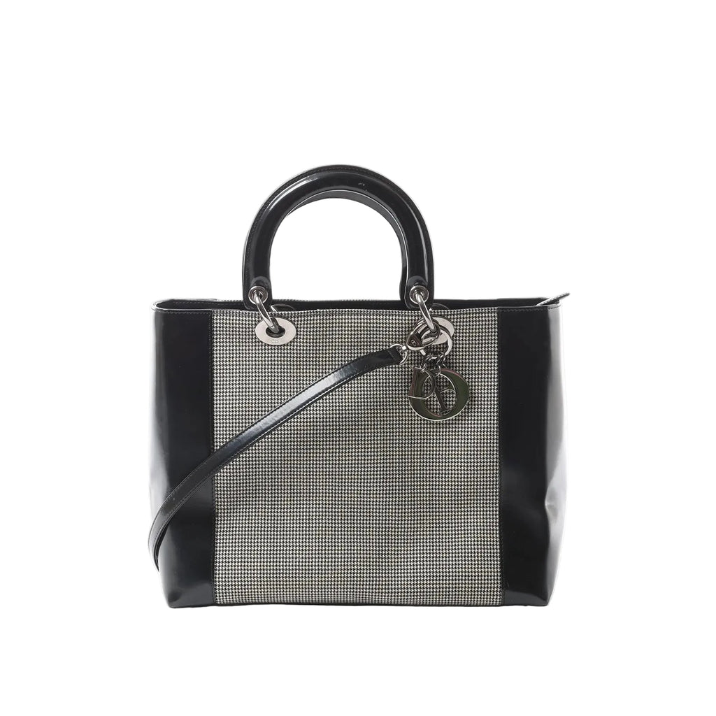 Dior Lady Dior handbag with black patent leather sides and handles, black-and-white canvas panel, silver-tone hardware, and hanging Dior letter charms.
