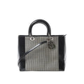 Dior Lady Dior handbag with black patent leather sides and handles, black-and-white canvas panel, silver-tone hardware, and hanging Dior letter charms.