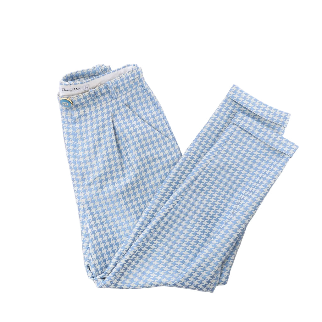 Christian Dior blue and white houndstooth cotton pants laid flat with belted waist detail, pleated cuffs, and visible Dior label on white background.