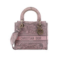 Dior Lady D-Lite Medium pink Toile de Jouy embroidered canvas handbag with top handles, shoulder strap, CHRISTIAN DIOR front logo, and gold-tone DIOR charms on white background.