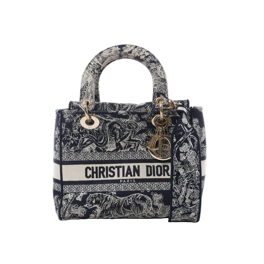 Dior Lady D-Lite Medium handbag in navy blue and white embroidered canvas with Christian Dior logo band, gold-tone DIOR charms, top handles and detachable shoulder strap on white background.