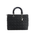 Front view of Dior Lady Dior Large handbag in black Cannage quilted denim with glossy black top handles, silver-tone hardware, and hanging DIOR letter charms.