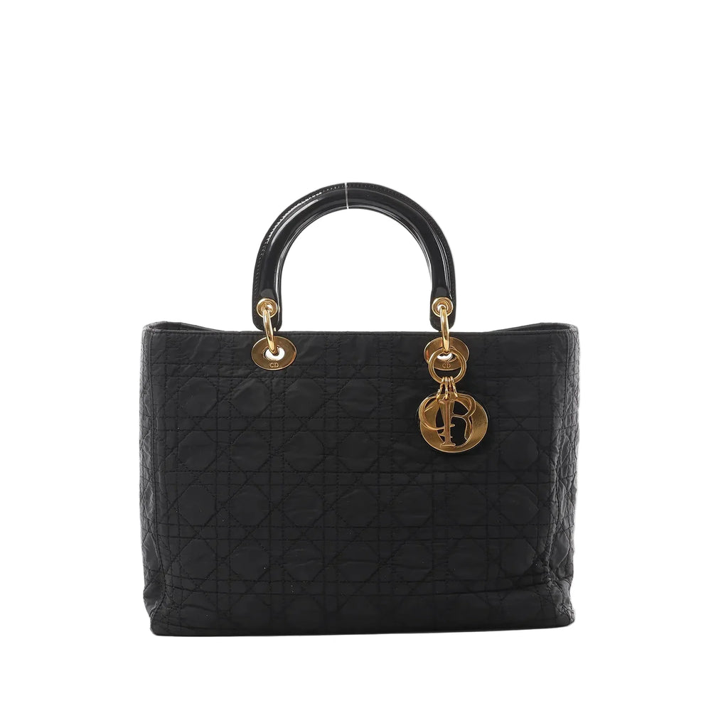 Dior Lady Dior Large black Cannage quilted nylon handbag with patent top handles, gold-tone ring hardware, and dangling DIOR letter charms on a white background.