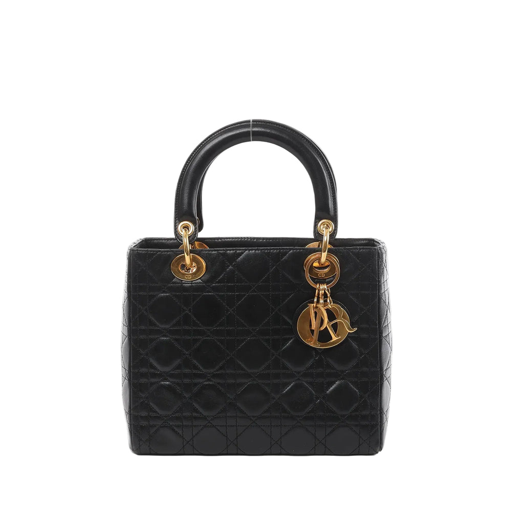 Black cannage quilted leather Dior Lady Dior top-handle handbag with gold-tone hardware and dangling letter charm, photographed on a white background.