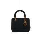 Front view of Christian Dior Lady Dior black nylon handbag with Cannage stitching, rounded top handles and gold-tone hardware and Dior letter charms.