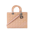 Front view of Dior Lady Dior Large handbag in beige patent Cannage quilted leather with rounded top handles, silver-tone hardware, and hanging DIOR letter charms.