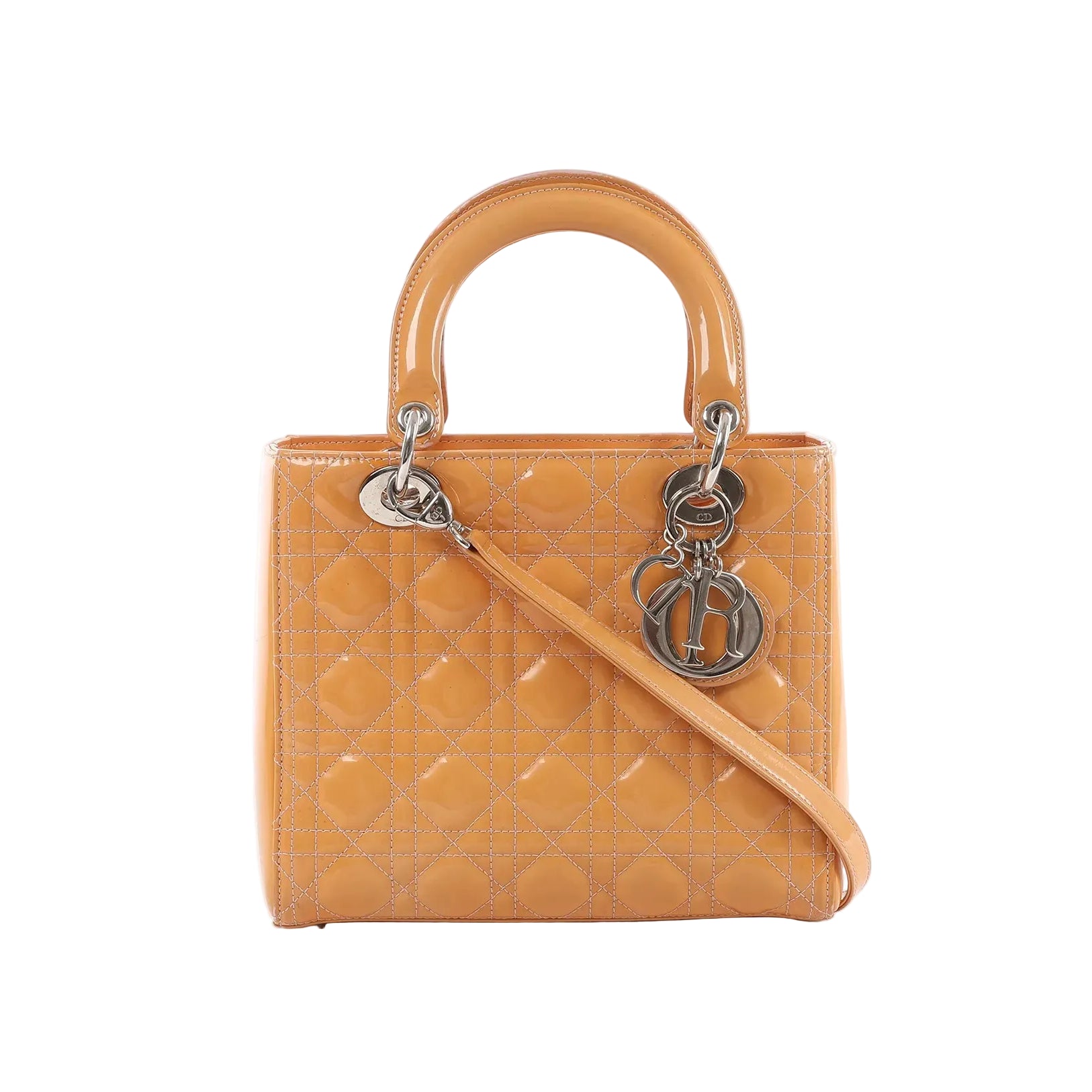 Front view of Dior Lady Dior Medium handbag in orange patent leather with Cannage quilting, structured top handles, detachable shoulder strap, and silver-tone letter charms.