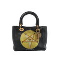 Dior Lady Dior medium black leather handbag with top handles, gold-tone DIOR letter charms, and a circular “Swords” tarot graphic on the front.