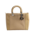 Beige Christian Dior Lady Dior handbag with canvas center panels, smooth leather sides and handles, silver-tone hardware and hanging DIOR charms.