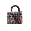 Dior Lady Dior Small handbag in black, white, and red tweed with glossy black top handles, black patent leather shoulder strap, and silver-tone DIOR charms on white background.