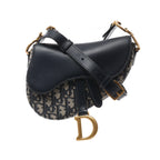 Navy Dior Saddle Mini Oblique canvas crossbody bag with black leather flap and strap, gold-tone hardware and large D charm.